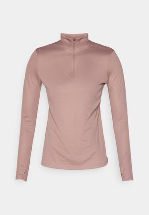 Pitkähihaisen, vetoketjullisen yläosan pehmeässä vaaleanpunaisessa kankaassa. Tiukka istuvuus, teksturoitu pinta ja suora helma, sopii urheilulliseen käyttöön.