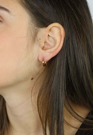 Orecchino a cerchio dorato su un lobo, con una finitura metallica lucida. Il design è circolare con una superficie liscia che riflette la luce.