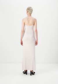 Dlouhé, úzké šaty z jemné růžové látky s tenkými ramínky a bočními rozparky. Mají jednoduchý, hladký design a elegantní siluetu.