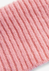 Tessuto in maglia rosa con una texture a coste, caratterizzato da morbidi e soffici filamenti che creano profondità e dimensione. Adatto per abbigliamento o accessori.