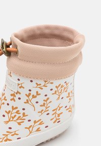 Botte de pluie en caoutchouc blanc pour enfants avec motif de branches orange et points bordeaux, bord en mesh rose et cordon de serrage en cuir ajustable.
