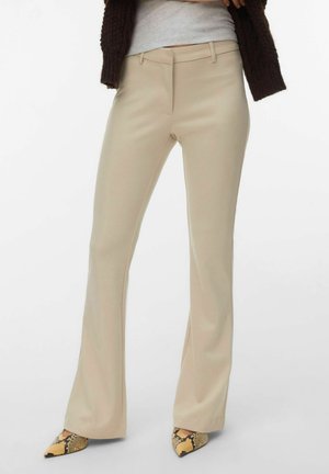 Pantaloni beige a gamba dritta indossati con una maglia grigio chiaro, un cardigan lavorato a maglia marrone scuro e décolleté a punta con stampa serpente.