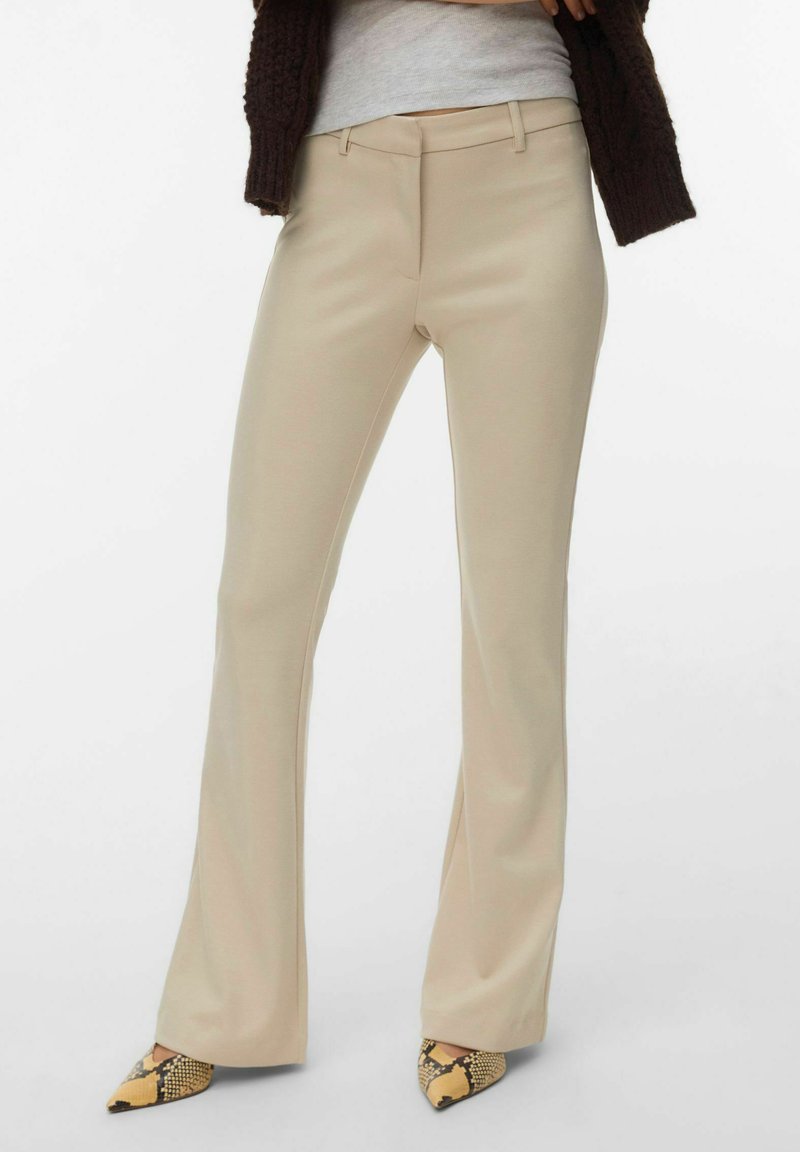 Pantalon beige à jambes droites porté avec un haut gris clair, un cardigan en tricot marron foncé et des talons pointus à imprimé serpent.