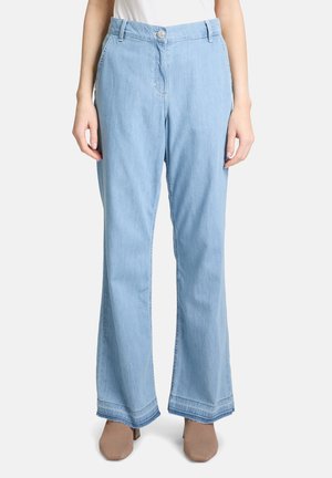 Pantaloni a gamba larga in denim azzurro chiaro con vita alta, chiusura con bottoni frontali e orlo sfilacciato. Abbinati a scarpe beige.