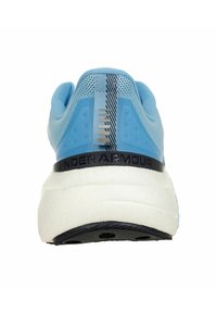 Baskets de sport bleu clair avec une tige texturée, logo noir "UNDER ARMOUR" et une semelle texturée blanche. Présente un talon à motifs.