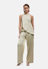 Lichtgroene, gestructureerde crop top met een asymmetrische zoom, gecombineerd met wijde broek in bijpassende stof. Eenvoudig ontwerp met minimale hardware.