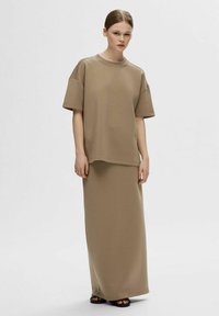 Beige oversized t-shirt med korteærmer, parret med en matchende maxi-nederdel. Blødt stof, afslappet pasform og enkelt design, minimale detaljer.