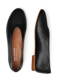 Černé kožené nazouvací boty s hnědými stélkami a dřevěnými nízkými podpatky, zobrazené jedny shora a jedny z boku na bílém pozadí.