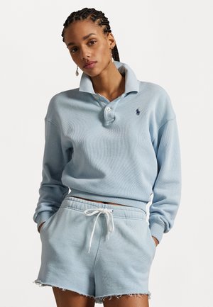 Pulover din bumbac de culoare albastru deschis, cu guler, două nasturi și logo brodat; asortat cu pantaloni scurți cu siret, având margini destrămate.