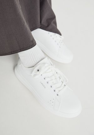 Zapatillas deportivas de cuero blanco con diseño de cordones, suela de goma texturizada y pequeñas perforaciones. Logo de la marca "Levi's" exhibido en el lateral.