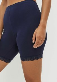 Navyblauwe fietsshorts van gladde stof, voorzien van een decoratieve kantafwerking aan de rand en een nauwsluitend ontwerp.