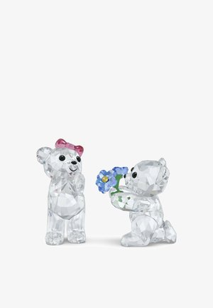 Figurines en cristal de deux ours ; l'un avec un nœud rose, l'autre tenant une fleur bleue au centre jaune, toutes présentant des détails facettés.