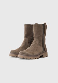 Botas de tobillo de ante marrón con paneles laterales elásticos, punta redondeada y una suela de goma resistente que presenta un patrón de agarre texturizado.