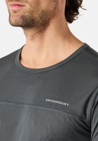 Graues Sportshirt mit strukturiertem Muster, Rundhalsausschnitt und weißem "SWEDEMOUNT"-Logo auf der Vorderseite. Kurzärmlig, taillierte Passform.