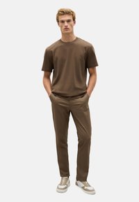 Bruine katoenen crewneck t-shirt gecombineerd met bijpassende op maat gemaakte broek en beige sneakers, met een zachte textuur en een casual pasvorm.