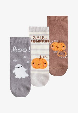 Trzy skarpetki w tematyce Halloween z nadrukami: duch z napisem „boo!”, uśmiechnięta dynia z napisem „mała dynia” oraz dwie dynie z napisem „cukierek albo psikus”.