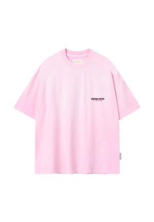 Lyserød kortærmet T-shirt med rund halsudskæring og lille sort og rød tekst "ANOTHER COTTON OUT OF OFFICE" på venstre bryst.