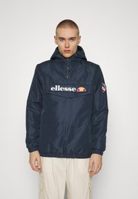 Giacca a pullover con cappuccio di colore blu navy, dotata di tasca frontale, polsini elasticizzati e patch con logo. Realizzata in materiale liscio e leggero.