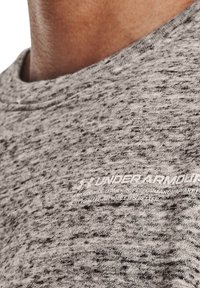 Maglietta atletica grigia a maniche corte con un motivo testurizzato. Presenta un collo rotondo e un marchio stampato bianco sul lato inferiore.