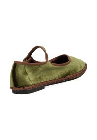 Zapatilla de terciopelo verde con ribete marrón, presenta una puntera redonda y tira en el tobillo, además de un detalle de textura tejida a lo largo de la suela. Suela plana de goma.
