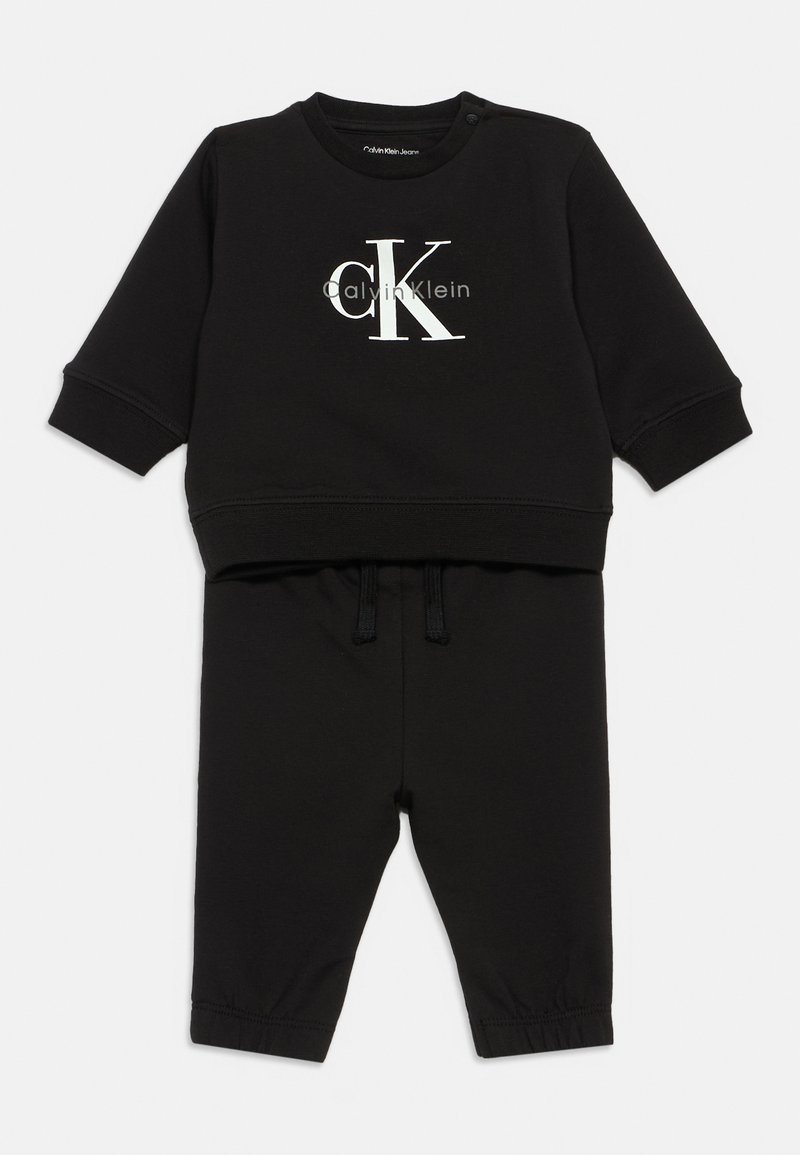 Conjunto de sweatshirt e calças para crianças negras, feito de tecido macio. Apresenta um logo branco "CK", punhos canelados e uma cintura elástica com cordões.