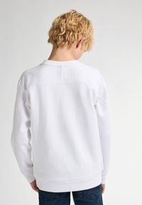 Witte sweatshirt met een ronde halslijn, ribbelmanchetten en -zoom. De stof lijkt zacht met een gladde textuur. Minimalistisch ontwerp, geen patronen.