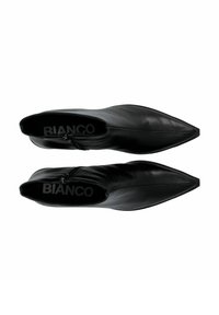 Bottines noires en cuir avec un design à bout pointu, dotées d'une fermeture éclair sur le côté et d'une texture lisse. L'intérieur comprend une semelle intérieure à logo.