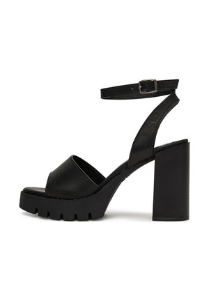 Fekete nyitott orrú, magas sarkú szandál vastag talppal, tömbszerű sarkal és csatos bokapánttal.