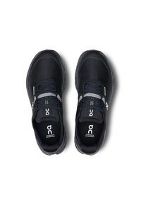 Baskets de course noires imperméables avec un dessus texturé, fermeture à lacets et détails du logo sur la languette et les côtés. Forme de pointe arrondie.