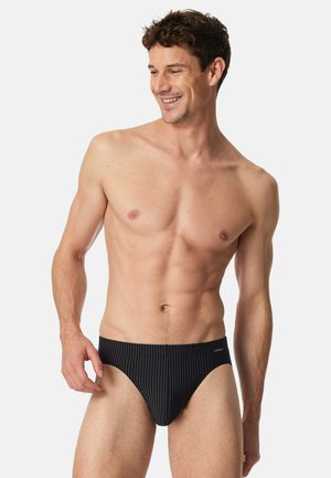 Zwarte zwembroek met verticale witte streepjes, voorzien van een laag uitgesneden ontwerp en een elastische tailleband voor een ideale pasvorm.