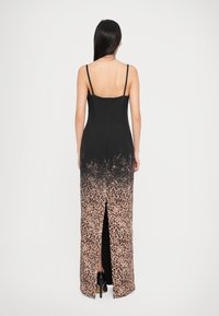 Robe maxi noire et imprimé animal avec un corsage ajusté, des bretelles spaghetti et une fente haute, présentant un motif léopard au niveau de l'ourlet.
