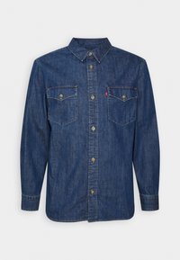 Chemise en denim bleu foncé à manches longues avec patte de boutonnage, deux poches poitrine plaquées avec boutons, et col pointu.