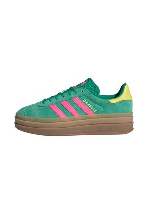 Groene suède Adidas Gazelle sneaker met roze strepen, gele hieltab en dikke gelaagde bruine zool, gezien van opzij.