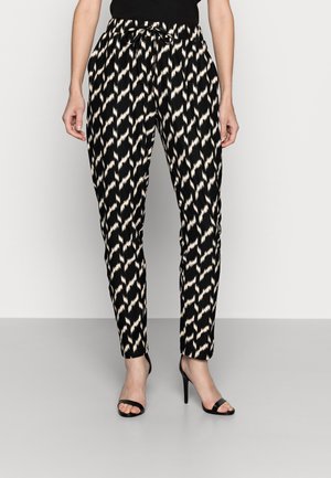 Schwarze und beige gemusterte, verjüngte Hose mit elastischem Bund und Kordelzug, getragen mit schwarzen Sandalen mit hohem Absatz.