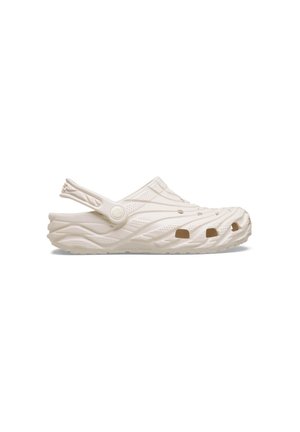 Sabot beige sans lacets avec trous de ventilation, semelle texturée et bride de talon réglable, vue de côté sur fond blanc.