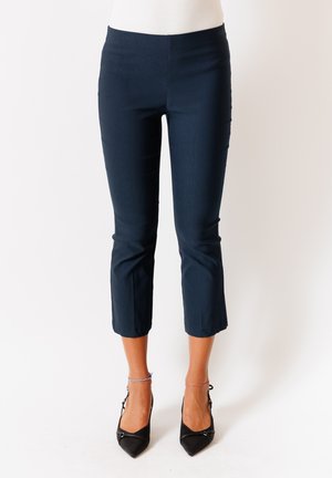 Pantaloni cropped blu navy in un tessuto liscio con un design aderente e una vita alta. Abbinati a tacchi neri a punta e dettagli alla caviglia.