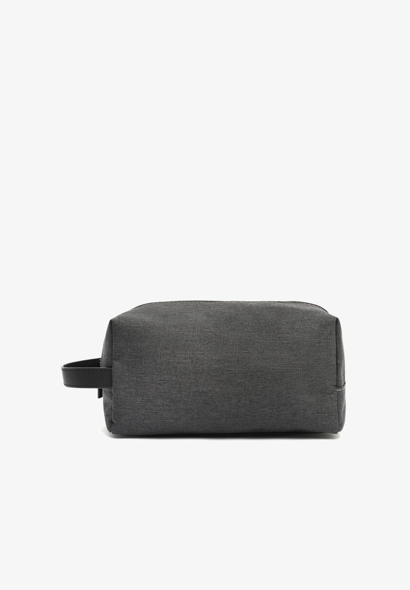 Pr rectangularna temno siva tkanina torba za toaletne potrebščine z črnim usnjenim ročajem na strani na belem ozadju.