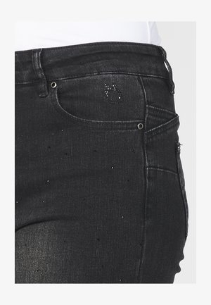 Mustad denimhallid, mis on slim fit lõikega, peene kulumise detailidega, sädelevate aksessuaaridega ning traditsioonilise viie taskuga disainiga.