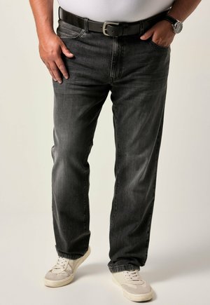 Jean en denim gris foncé avec une coupe décontractée, comportant cinq poches et une ceinture noire. Porté avec des baskets blanches. Texture lisse avec des détails décolorés.