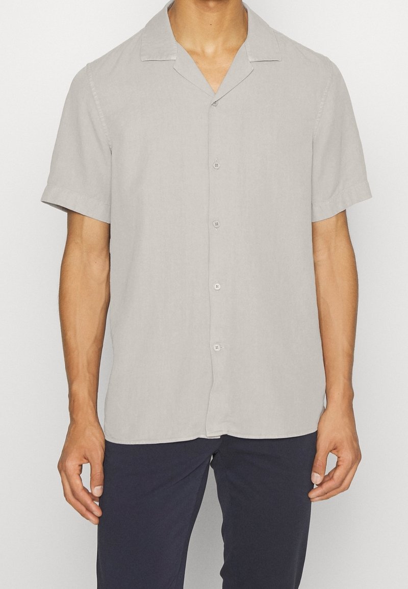 Camicia a maniche corte in tessuto grigio chiaro, con colletto a punta e vestibilità rilassata, dotata di chiusura a bottoni visibile e texture liscia.