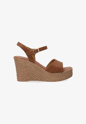 Hnědé kožené sandály na platformě s širokým otvorem na prsty, tenkým řemínkem kolem kotníku a tkaným korkovým podpatkem. Elegantní a moderní design.