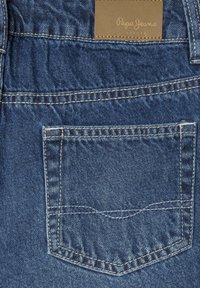 Tamno plave traperice s pozadinom džepom s kontrastnim šavovima i smeškom od smeđeg kože na kojem je utisnuto "Pepe Jeans London."