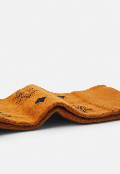 Orange sokker lavet af blødt materiale med sorte designs, inklusive et emblem og diamantmønstre, med synlig tekstur og foldet design.