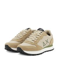 Beige Sneakers aus Wildleder und Mesh-Materialien, mit einem grünen Akzent an der Sohle, einer kontrastierenden schwarzen Zunge und einem Logodetail an der Seite.