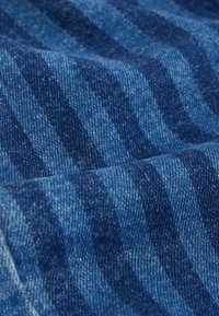 Jeansmaterial med olika nyanser av blått i ett randigt mönster, med en mjuk textur och subtil glans från fibervariation.