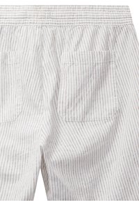Tissu blanc avec de subtiles rayures verticales marron, doté d'une ceinture élastique et de deux poches arrière carrées.