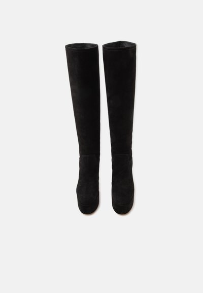 Paire de bottes cuissardes en daim noir avec bouts ronds et plateformes hautes, présentées côte à côte sur un fond blanc.