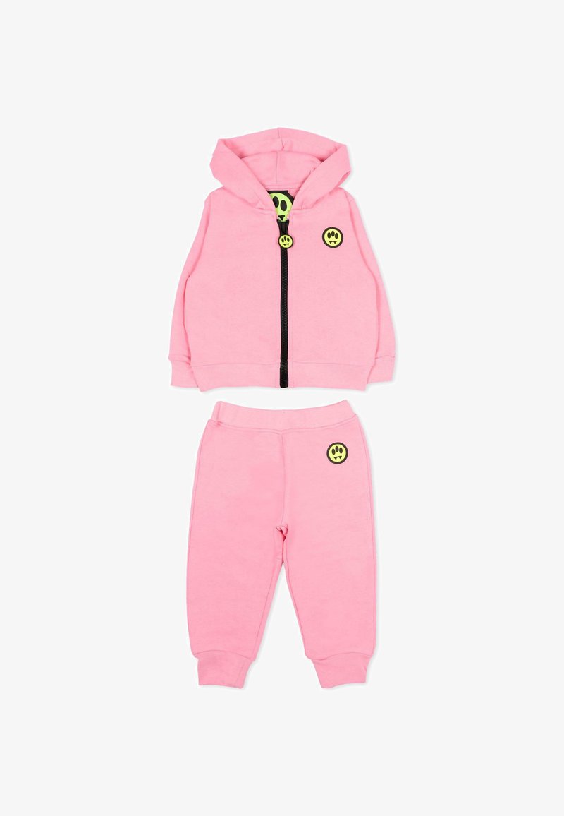 Ensemble pour tout-petit composé d'un sweat à capuche rose et d'un pantalon de jogging, avec des patchs de smileys jaunes et une fermeture éclair noire sur la veste.