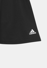 Black athletic skirt with a textured pattern. Features a white adidas logo on the lower right corner. Made of breathable material.