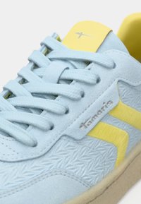Απαλά μπλε σουέτ αθλητικά παπούτσια με υφή, που διαθέτουν κίτρινες λεπτομέρειες και κορδόνια, ασημί λογότυπο και μπεζ καουτσούκ σόλα.